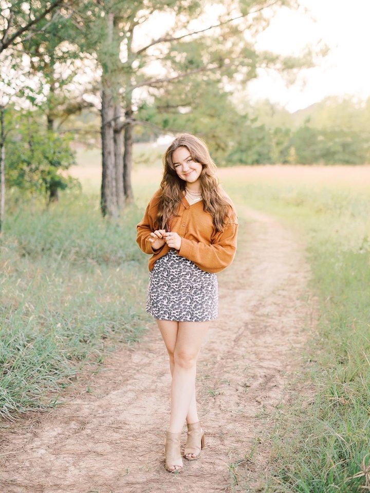 A high school senior walking a wooded path at golden hour