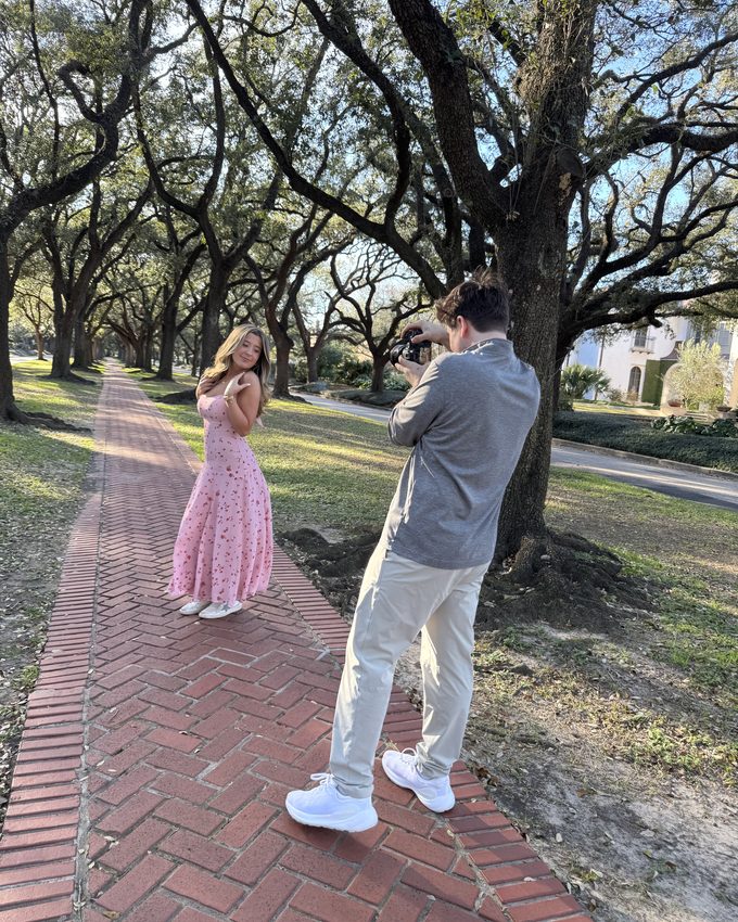 Reed holding a reflector while a senior is photographed on a trail